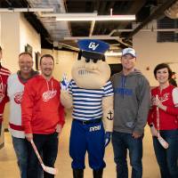 Six alumni smile for a photo together with Louie the Laker at the Detroit Red Wings GVSU Night